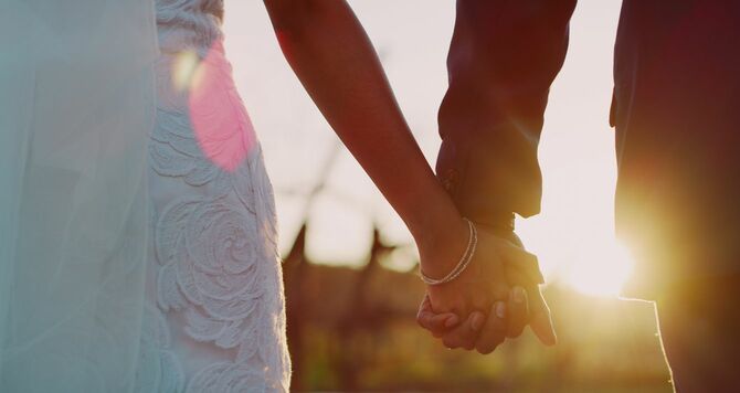 手をつないで外を歩く新婚カップル