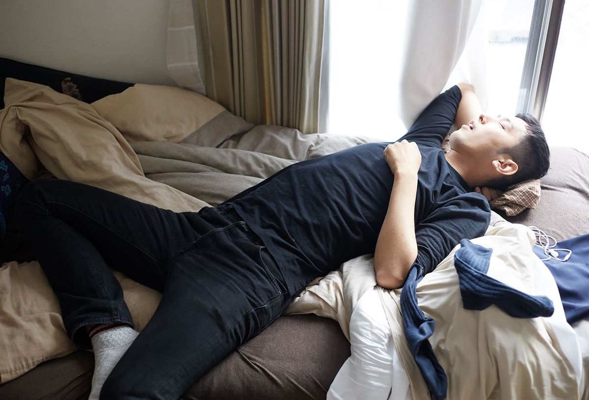 乱雑なベッドで昼寝をしている若い日本人男性