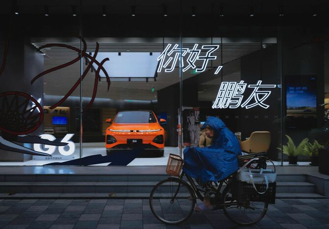 2023年9月15日、中国・上海で、中国の電気自動車メーカーXpeng社のショップの前を自転車で通り過ぎる女性。