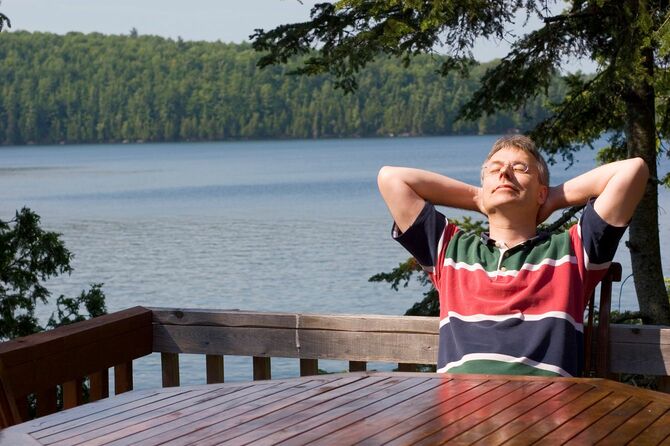 湖のほとりで陽にあたりながらリラックスする男性