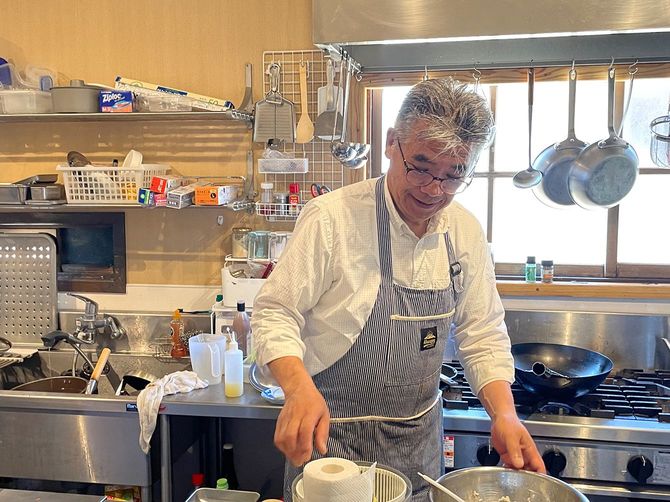まめな食堂のキッチンで料理中の更科安春さん