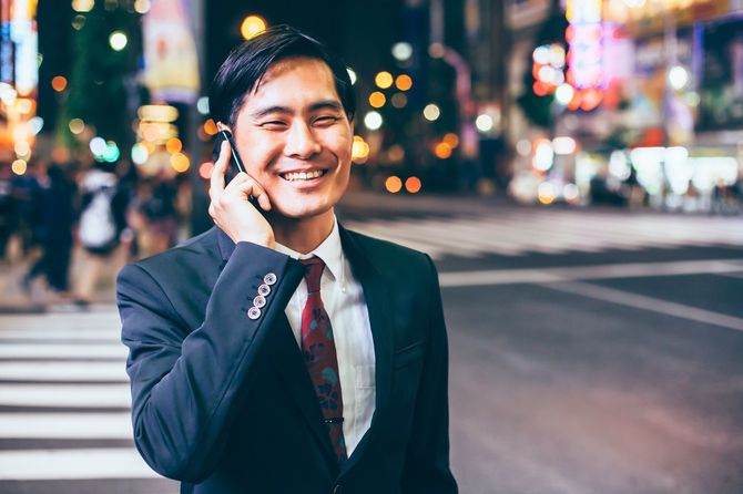 スマートフォンで話しながら横断歩道を渡るビジネスパーソン