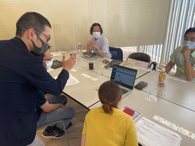 自治体職員に防災備蓄プラットフォームの特徴や使い方を説明をするベル・データの社員（左）ら＝沖縄県豊見城市