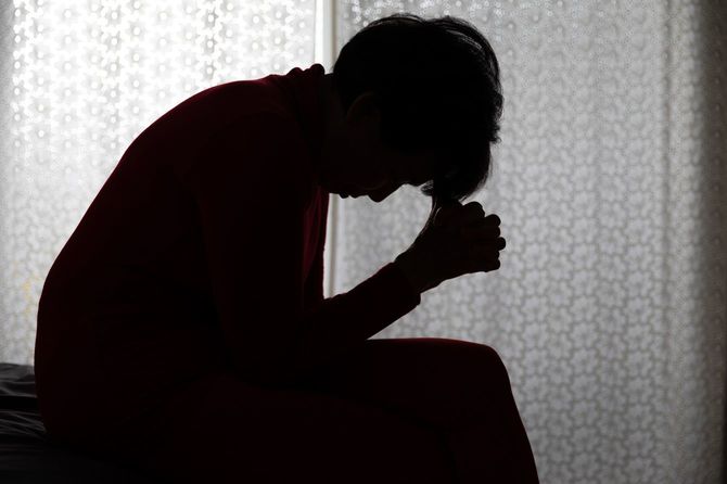 暗がりで頭を抱えている女性