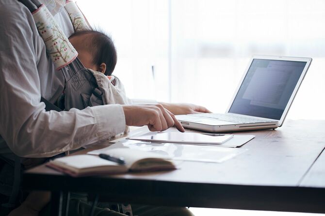 自宅で仕事の父親に抱かれた赤ちゃん