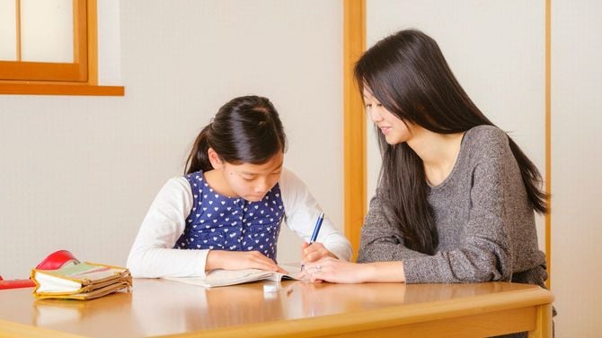 家庭教師と勉強を進める小学生