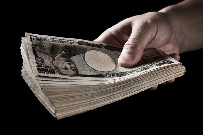 古札で100万円くらいの札束を差し出す男性の手元