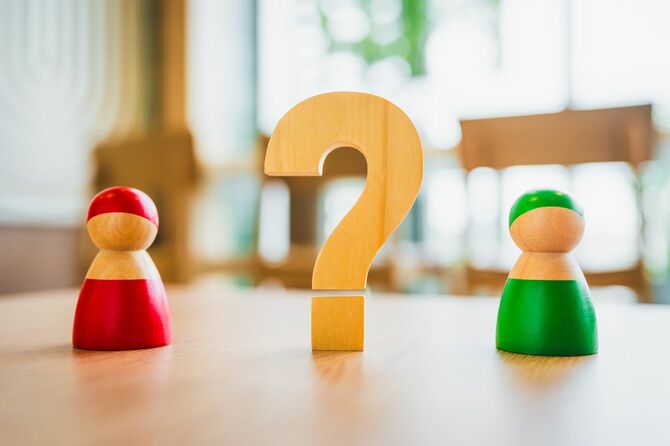 クエスチョンマークを挟んで立つ人のフィギュア