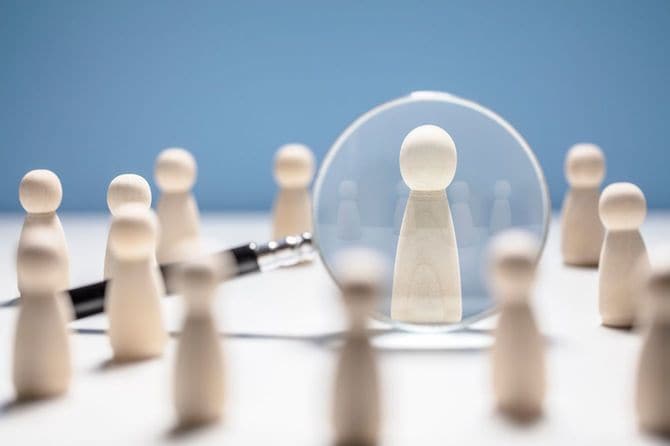 人形の木製ブロックが並んでいるうちの一人だけに拡大鏡が向けられている