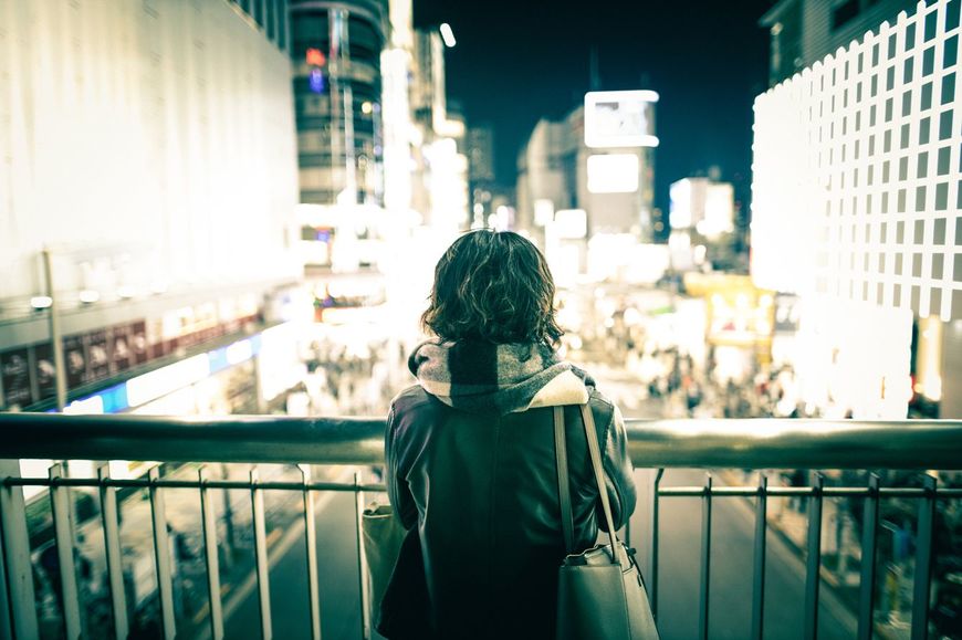 夜の歩道橋の上でたたずんでいる女性の後ろ姿