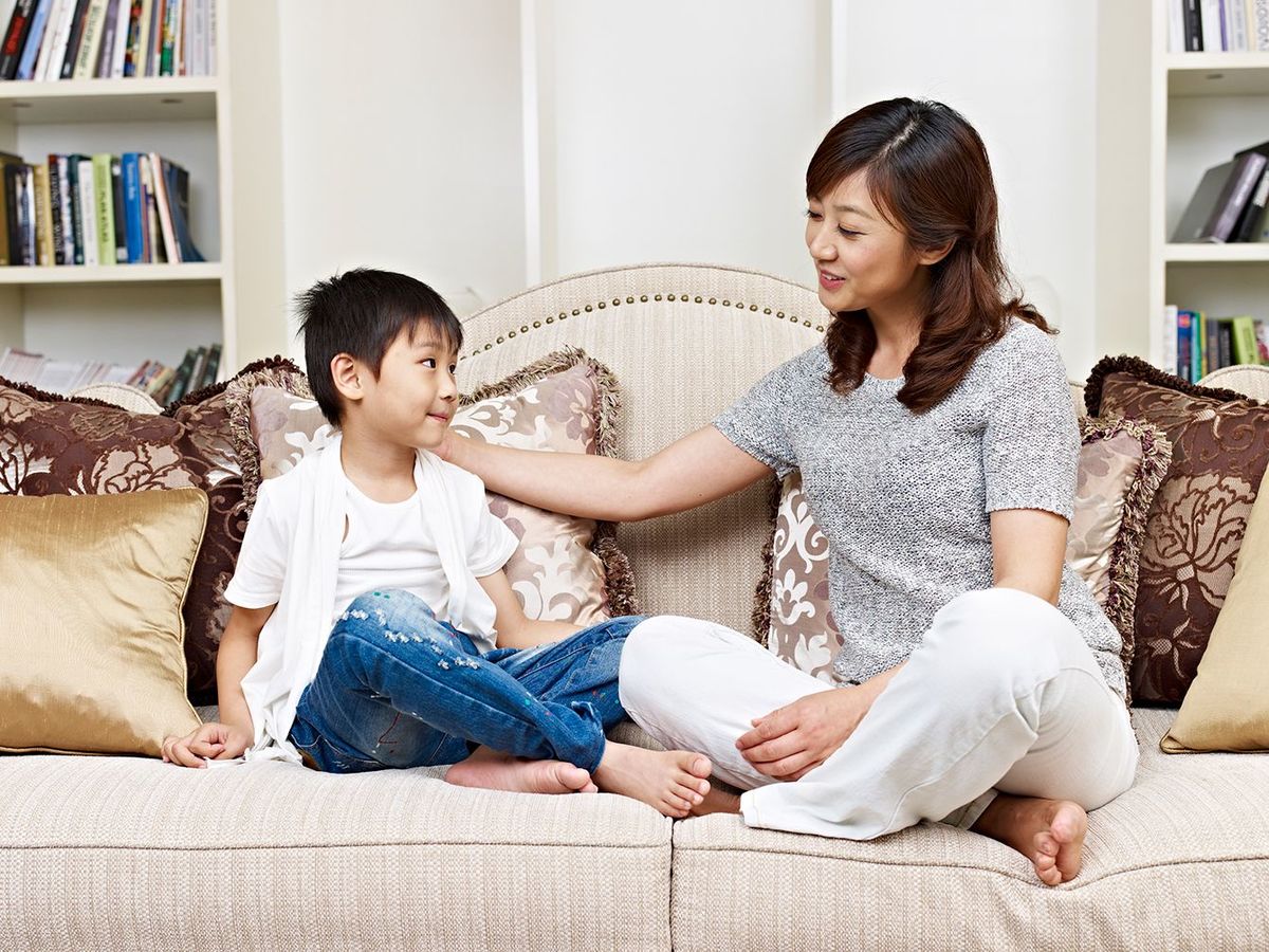 アジアの母と息子は自宅でソファで会話をしている