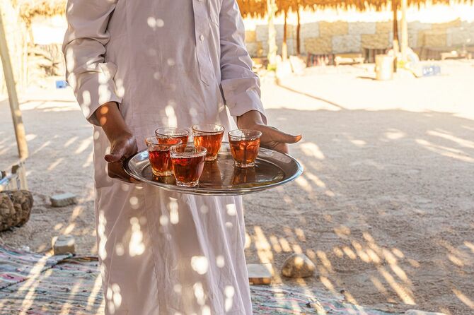 ウェイターの手に伝統的なエジプトのお茶のマグカップを持つトレイ。ベドウィンは、アーモンド、シナイとお茶のカップを歓迎します。