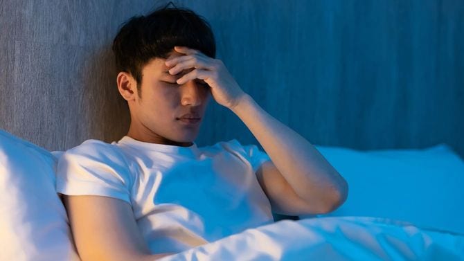 ベッドに入り、心配する男性