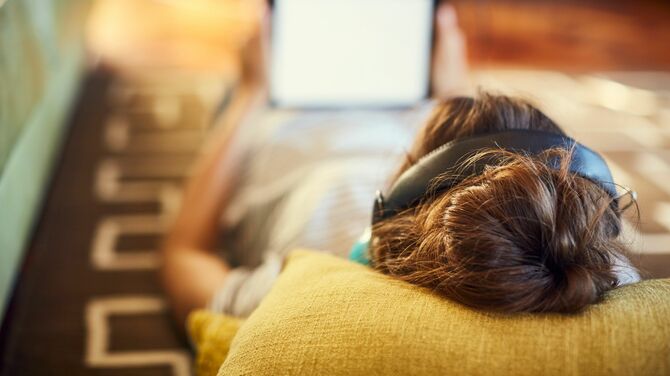 自宅で寝転がりながらタブレットを見る女性