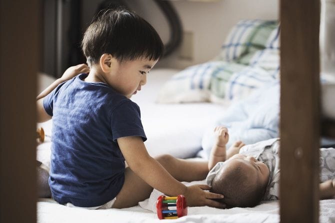 赤ちゃんの頭をなでる男の子