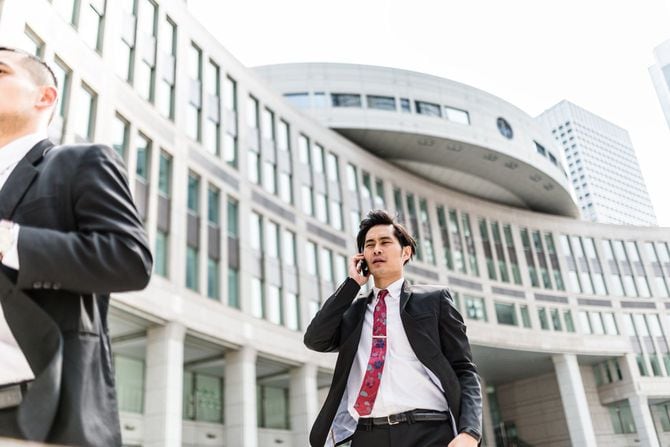 都民広場を電話をしながら歩くビジネスマン