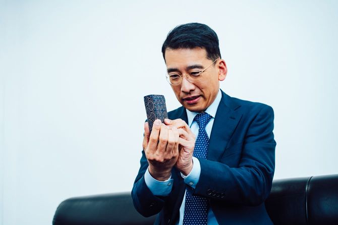 自身の名刺入れを手に取って、中古品査定のお手本を見せる遠藤代表