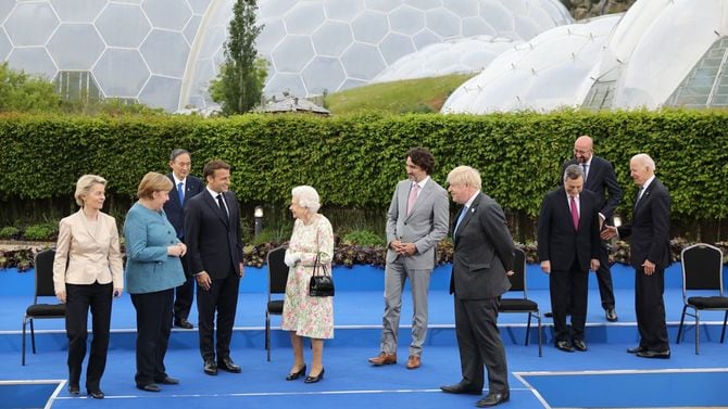 2021年6月11日、G7首脳会議の晩餐会前の写真撮影。左からメルケル首相（独）、マクロン大統領（仏）、中央のエリザベス女王を挟んでトルドー首相（加）、ジョンソン首相（英）。後方にいるのが菅義偉首相。