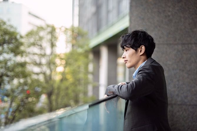 ベランダで考え事をする若いビジネスマン