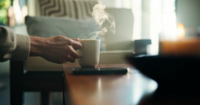 温かいコーヒーカップを持つ男性