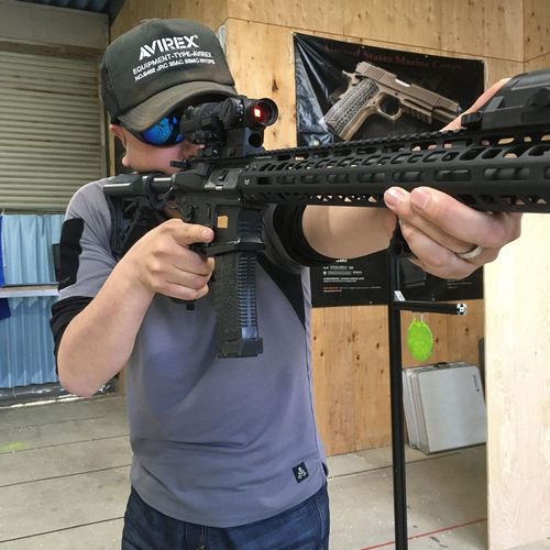 青い眼鏡をかけてゲーム用の銃をかまえる男性