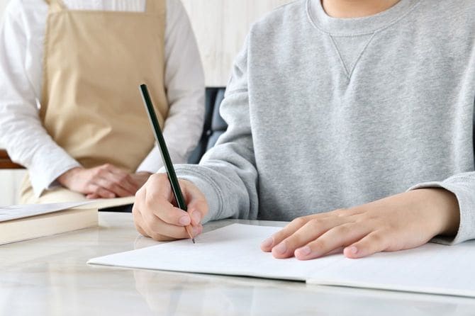 勉強している子供のそばで見守る母親