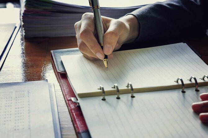 報告書から記録をつける男性