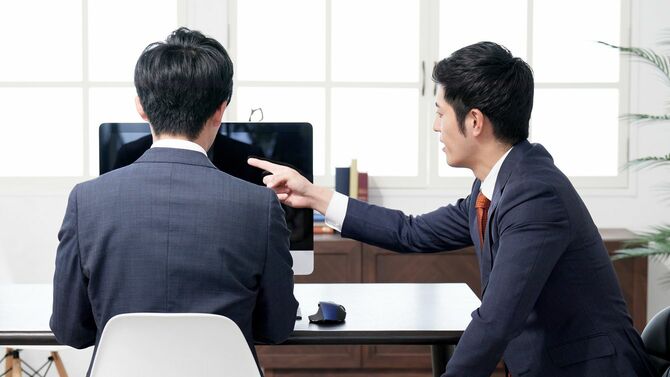 部下の横で指示を出すビジネスマン