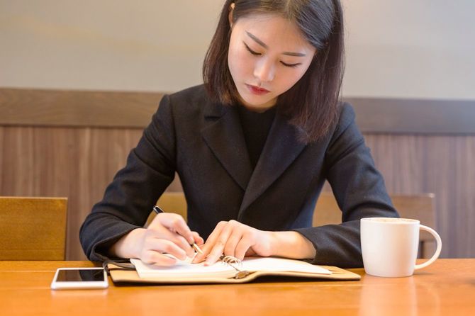 カフェのテーブルでノートを作るビジネスウーマン