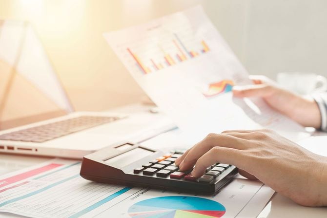 資料を見ながら電卓で計算する人