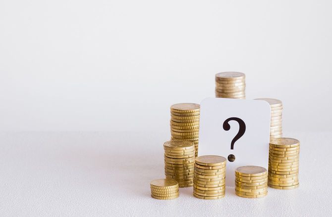 灰色の背景上のコイン スタックと疑問符。