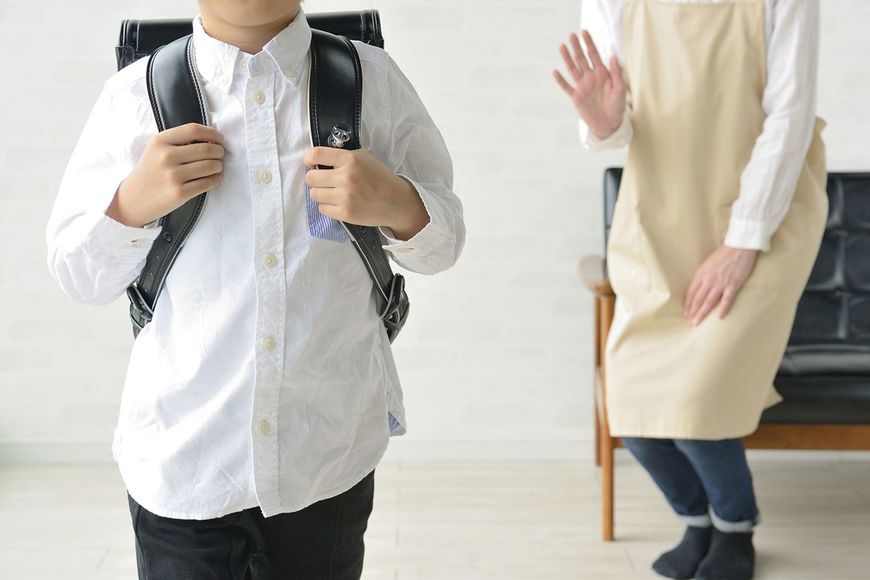 学校に行く少年と見送る母