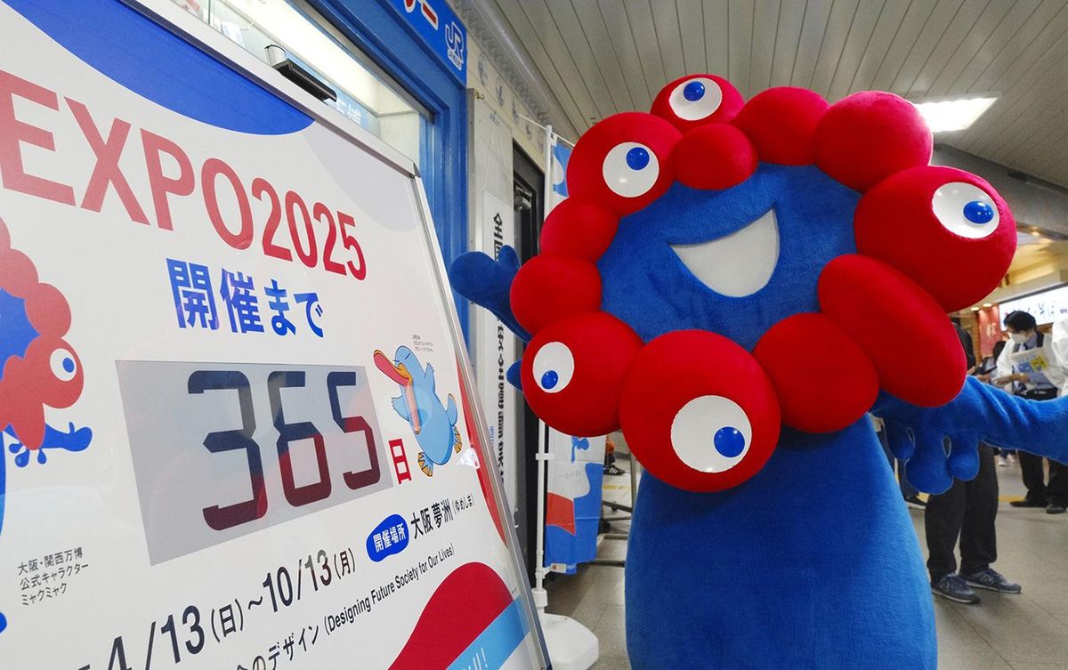 JR西九条駅で行われた大阪・関西万博をPRするイベントで、開幕まで「365日」を示すカウントダウン時計とポーズをとる公式キャラクター「ミャクミャク」＝2024年4月13日午前、大阪市