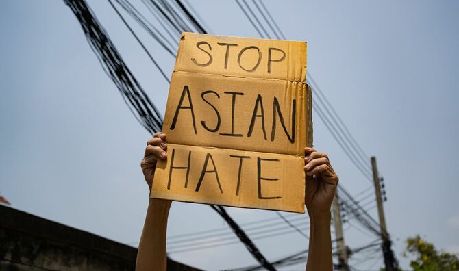 「アジア人への差別をやめて」という標語を書いた段ボールを掲げる人