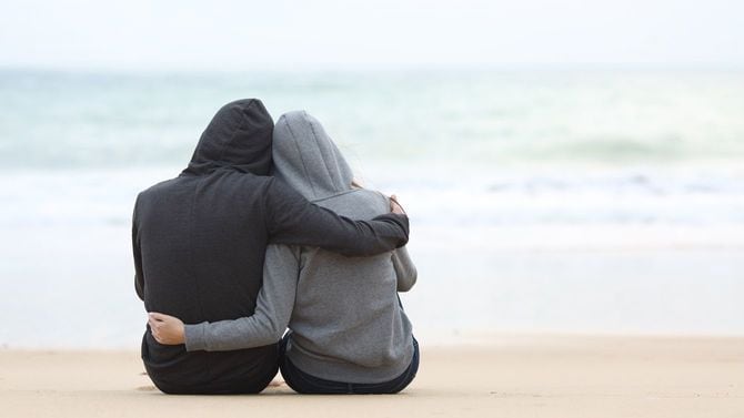 海を見ながらお互いをハグするティーンエージャーのカップル