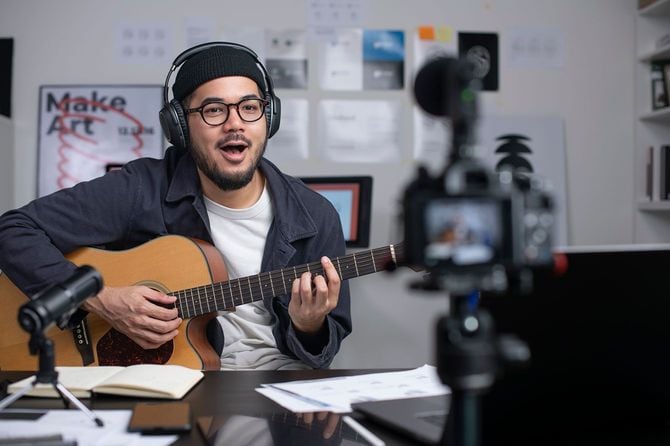 ギターのオンラインレッスンのために録画する男性