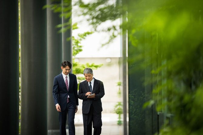 並んで歩く若いビジネスマンと高齢のビジネスマン