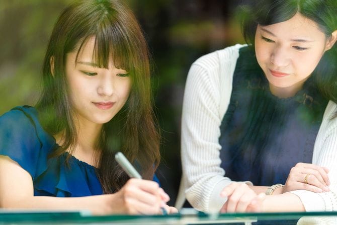 カフェで一緒に勉強する若い女性2人