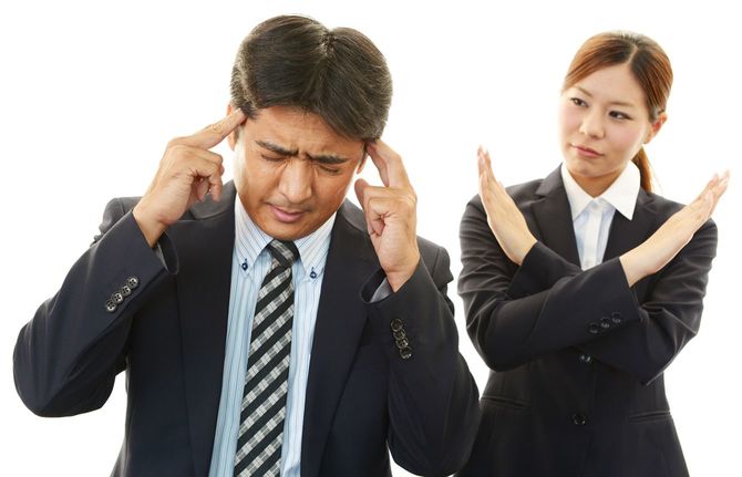 女性にバツ印を示され頭を抱えるビジネスマン