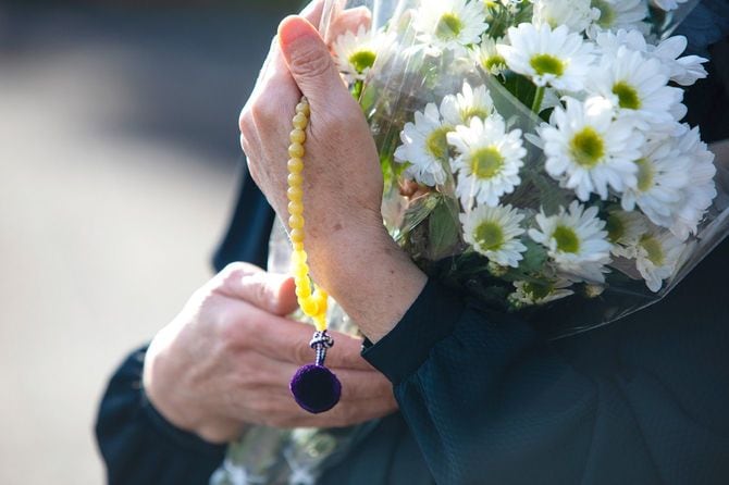 菊の花束を抱えて葬儀に参列する人