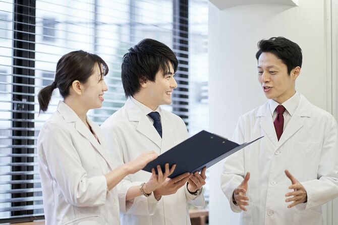 医師の話を聞く若い医療関係者