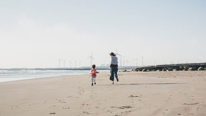 風力発電所に近いビーチを走る母と息子