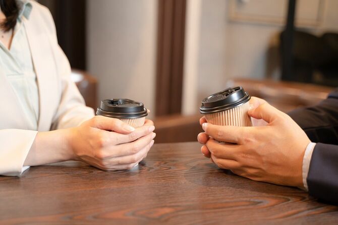 カフェでコーヒーを飲みながら話す男女
