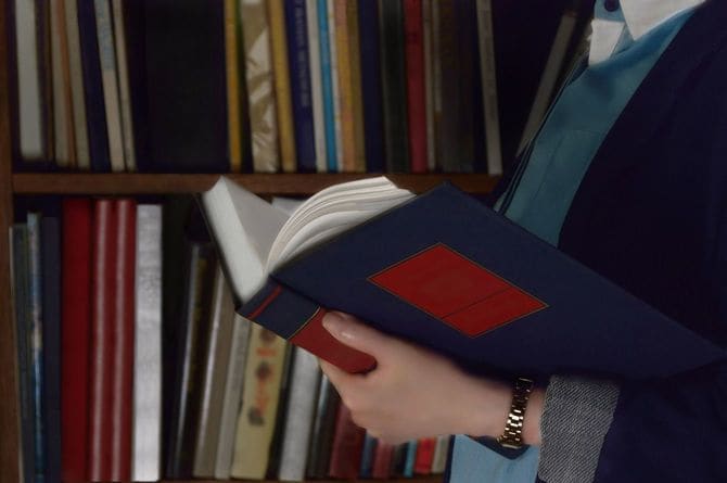 本棚の前で本を読む女性