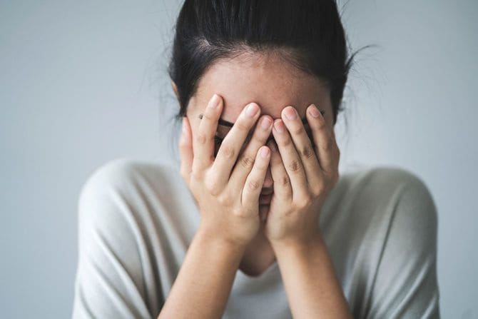手で顔を覆う女性