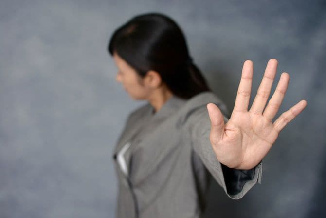 手でストップのサインを出す女性