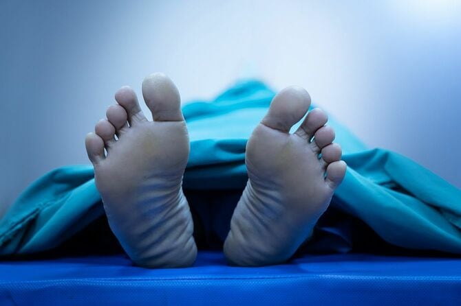 シートで覆われた死体の足