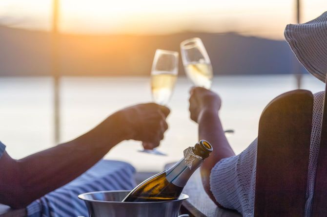ウォーターフロントのデッキチェアでシャンパンを飲みながらリラックスするカップル