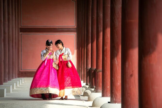 韓国の伝統衣装を現代風に再現した服を着た女性がスマホを見て笑っている