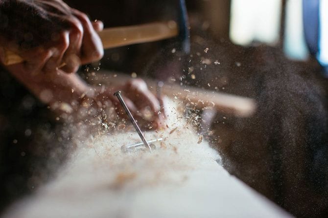 金槌で木材に釘を打つ人の手元